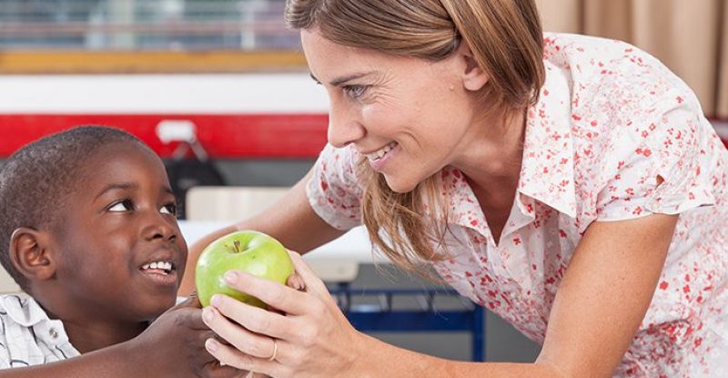 Boy giving to his teacher a apple